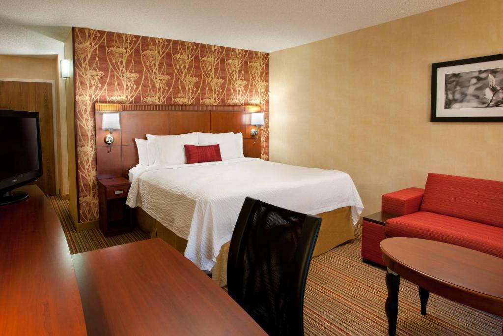 萨克拉门托纳透马斯萨克拉门托机场万怡酒店的酒店客房,配有一张床和一张红色椅子