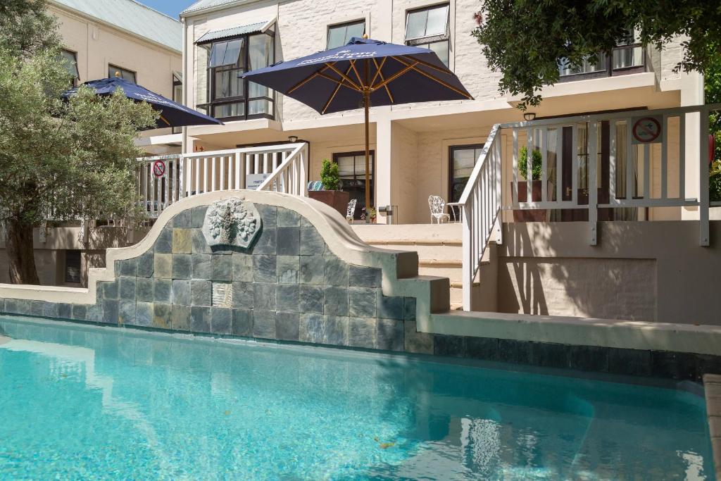 斯泰伦博斯Protea Hotel by Marriott Dorpshuis & Spa Stellenbosch的一个带楼梯和遮阳伞的游泳池