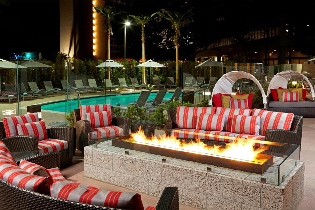 洛杉矶洛杉矶国际机场/世纪大道万豪酒店 的游泳池旁的火坑,配有沙发和椅子