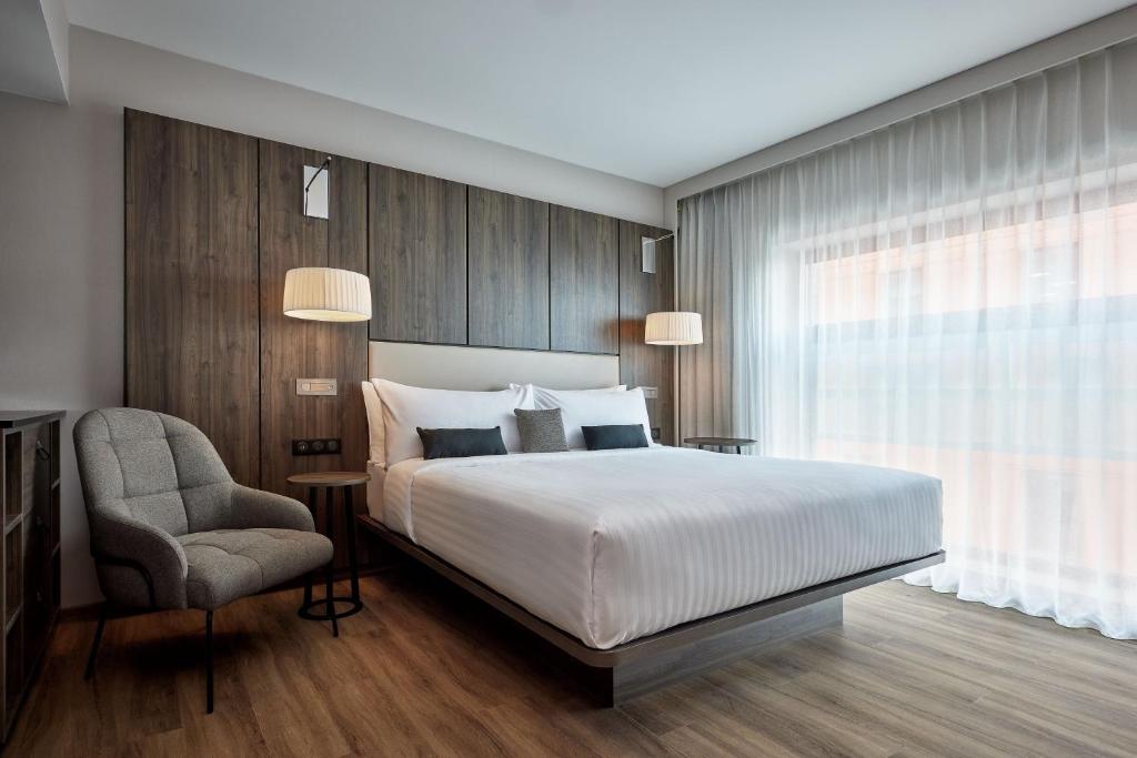 斯特拉斯堡AC Hotel by Marriott Strasbourg的卧室配有床、椅子和窗户。