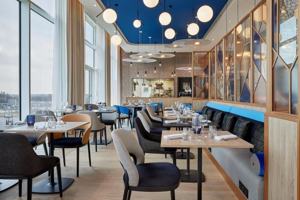 斯特拉斯堡AC Hotel by Marriott Strasbourg的餐厅设有桌椅和窗户。