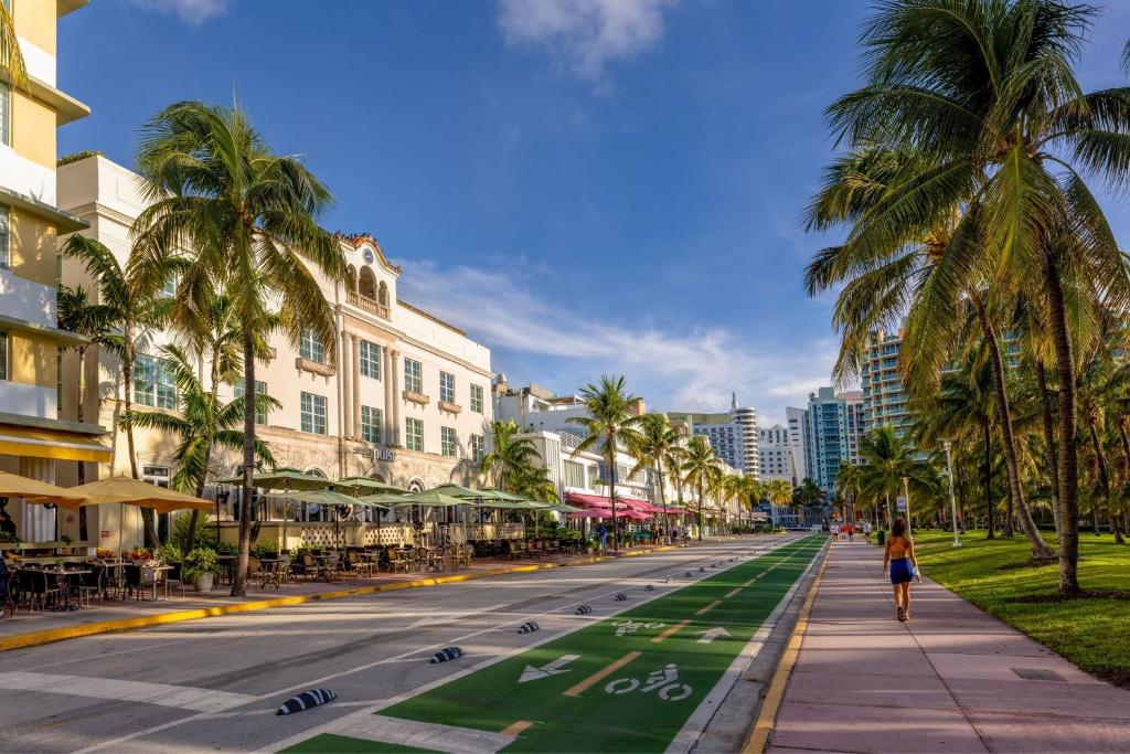迈阿密海滩Marriott Vacation Club®, South Beach   的一条有棕榈树和建筑的街道上走的女人