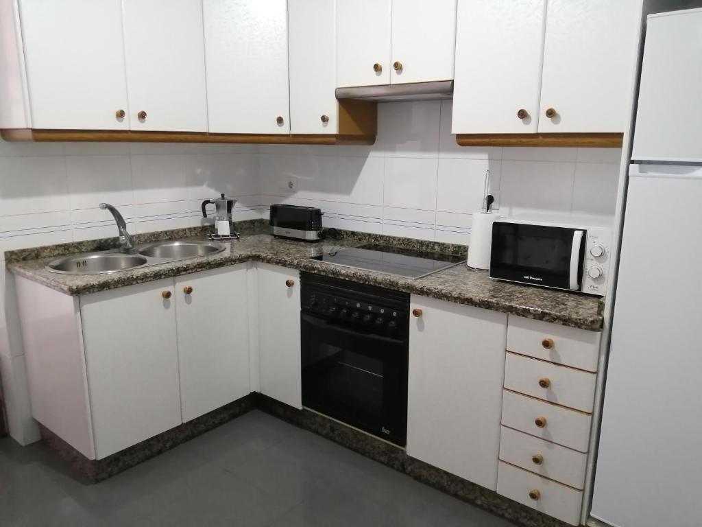 坎巴多斯O PISIÑO的厨房配有白色橱柜、水槽和炉灶。
