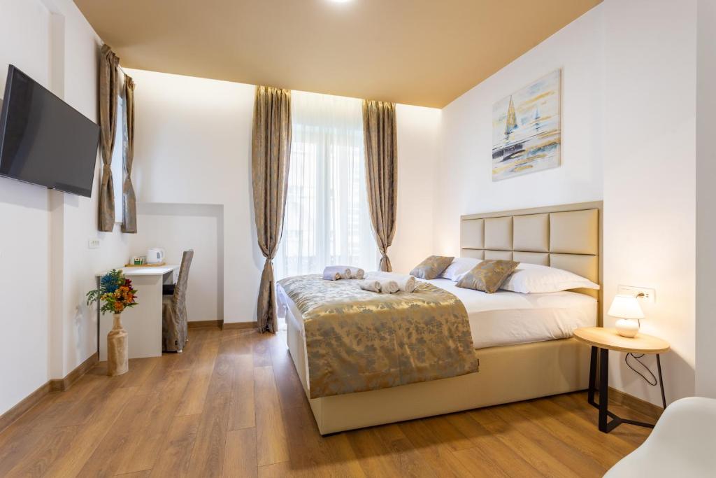 斯普利特Luxury Rooms Fetivi的一间卧室配有一张床、一张书桌和一台电视