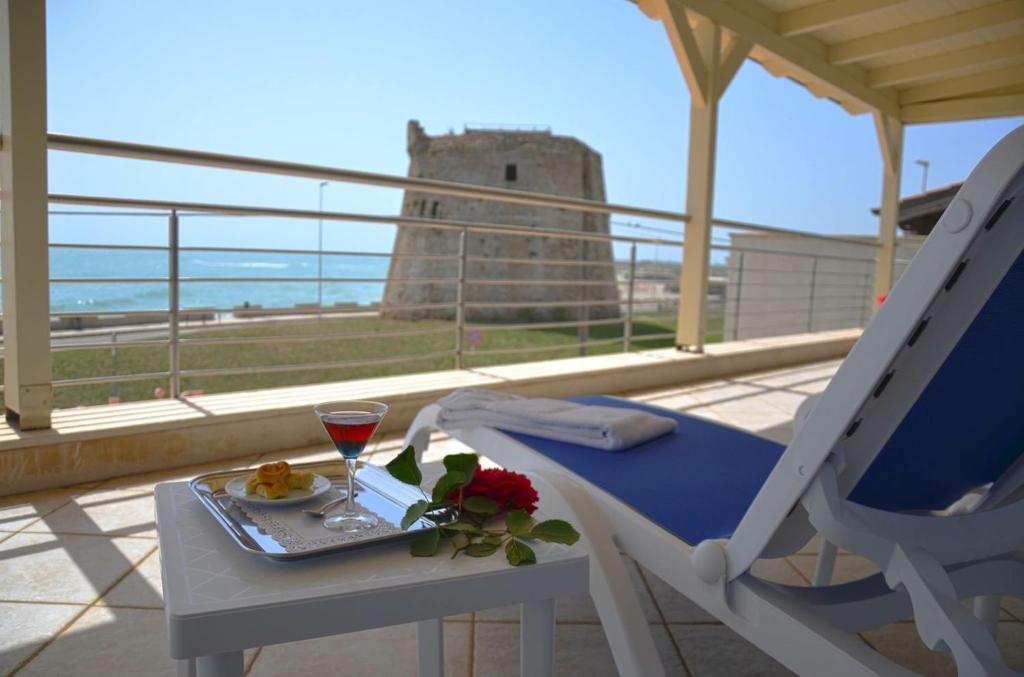 托雷莫泽Hotel Teti的城堡阳台的桌子上放着一杯葡萄酒