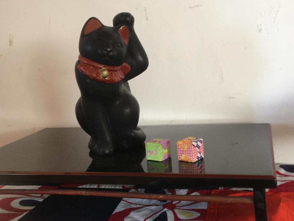 InamiMOMO HOUSE的坐在桌子上的一个黑猫雕像