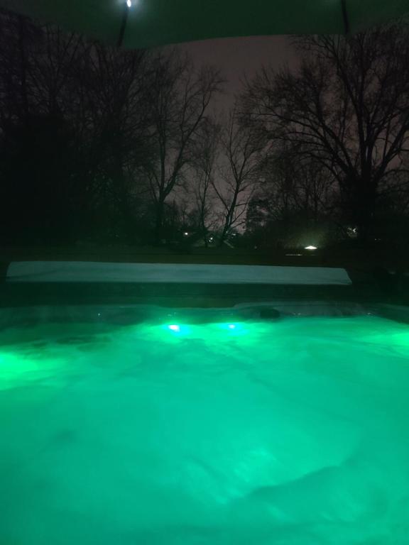 兰辛Outdoor Hot Tub and Cozy King Bed的游泳池的夜生活景与绿灯