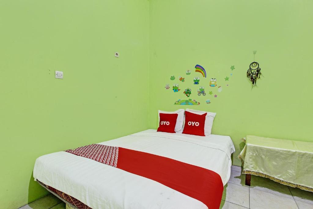 三宝垄OYO 92467 Cahyo Kost 1的一间卧室配有一张带两个红色枕头的床