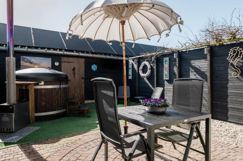 佩滕Strandhuis de Zeeparel met hottub的露台上的桌子和遮阳伞