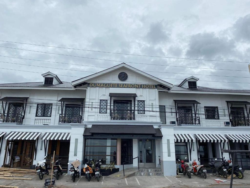 杜马格特Dumaguete Seafront Hotel的一座白色的建筑,前面停有摩托车