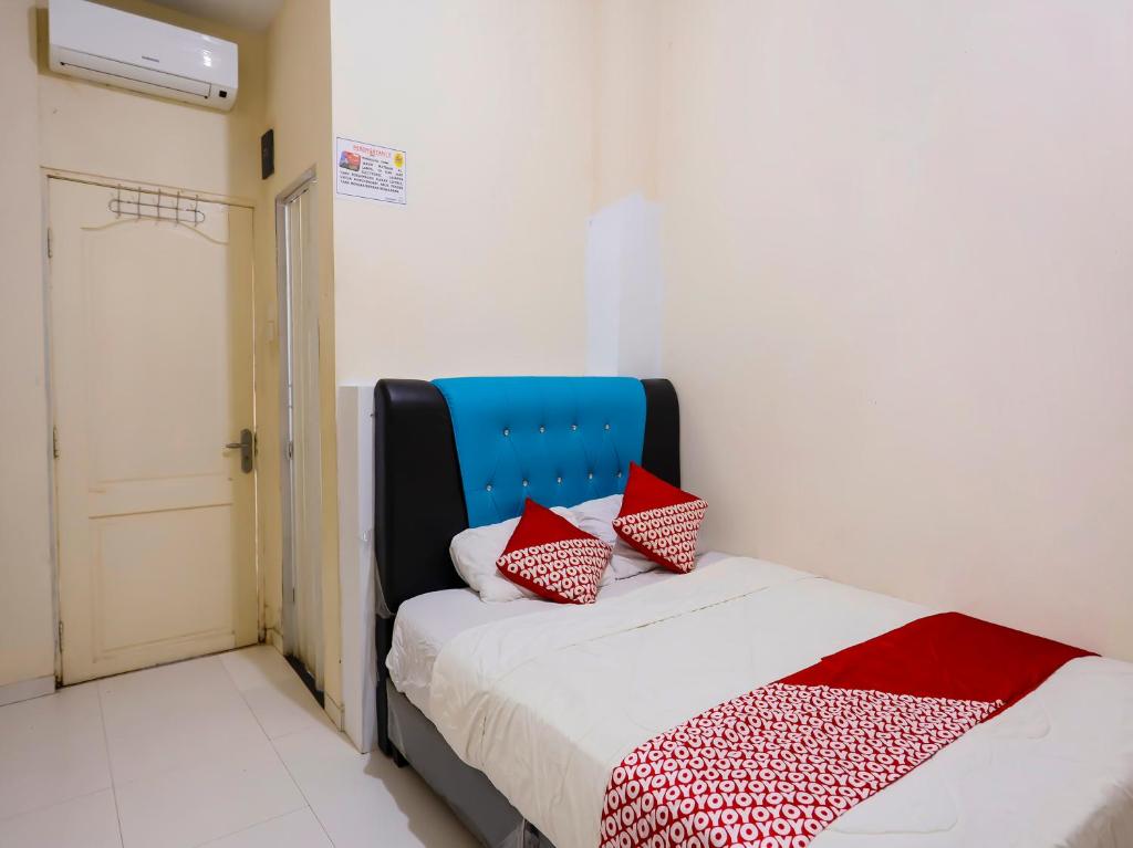 名古屋OYO 92451 Hasan House Syariah 2的一间卧室配有红色和白色枕头的床