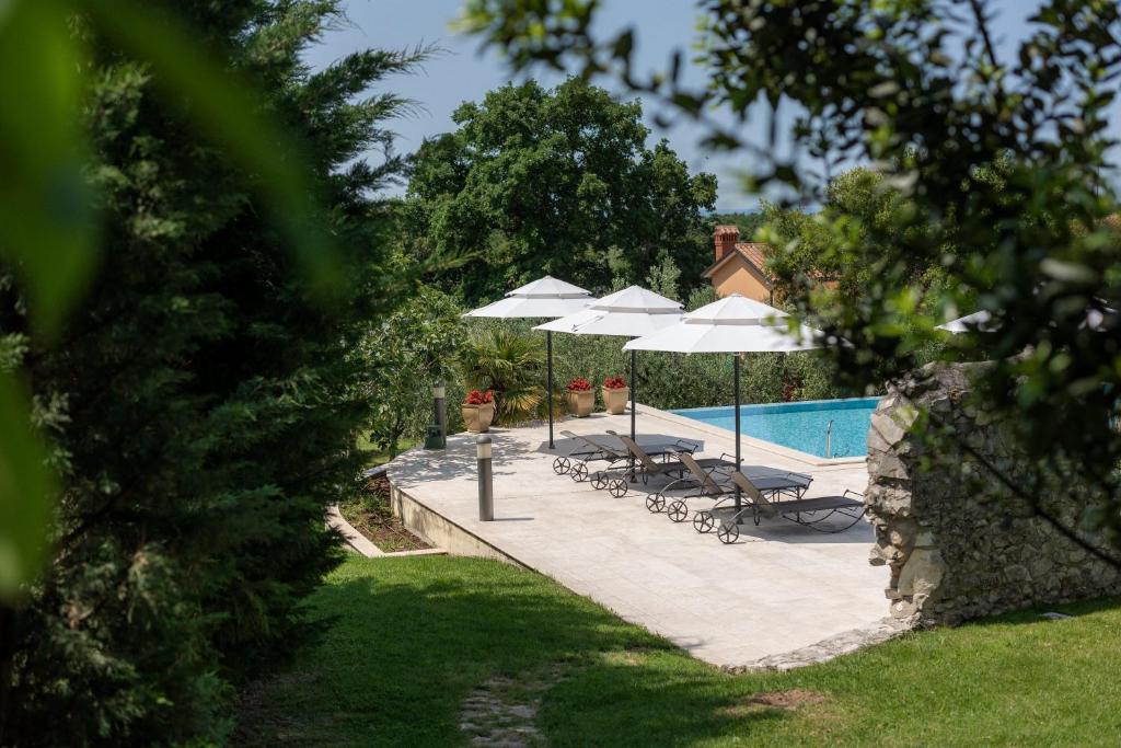 布罗托尼贾Heritage Hotel San Rocco的一个带遮阳伞和躺椅的游泳池以及一个游泳池