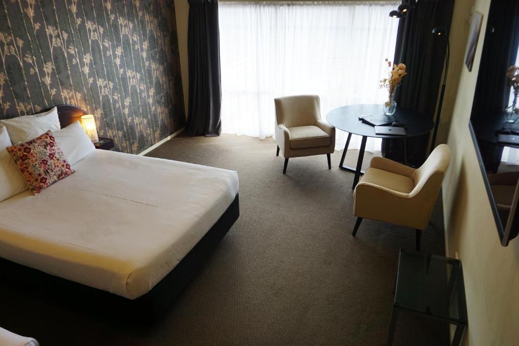 北帕默斯顿B-Ks Premier Motel Palmerston North的酒店客房带一张床、一张桌子和椅子