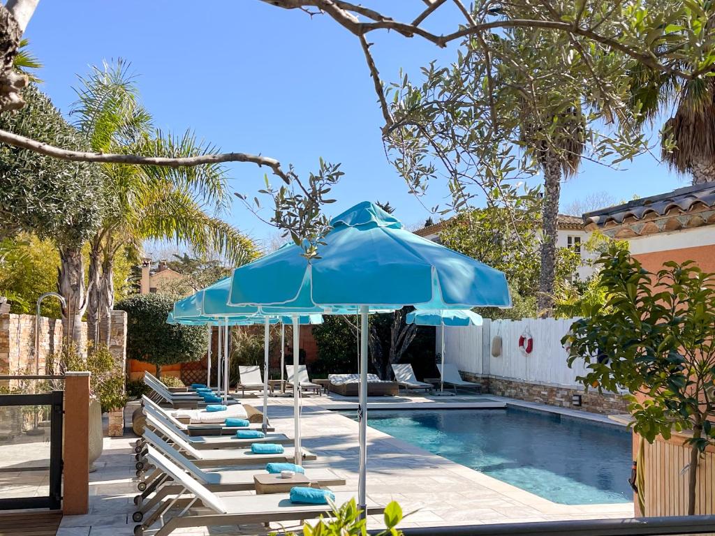 圣特罗佩乐莫伊拉格酒店的一组躺椅和一把遮阳伞,位于游泳池旁
