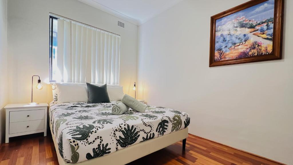 悉尼Carlton 3 beds unit - free parking的卧室配有一张床,墙上挂着一幅画