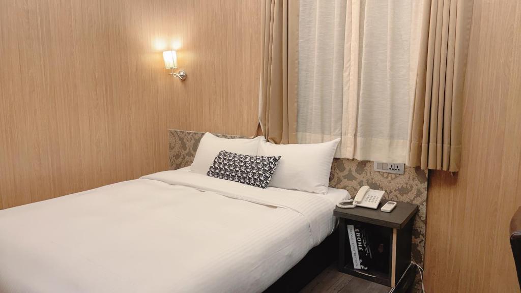 台北唯乐米窝的一间酒店客房,配有一张床铺和一张桌子上的电话