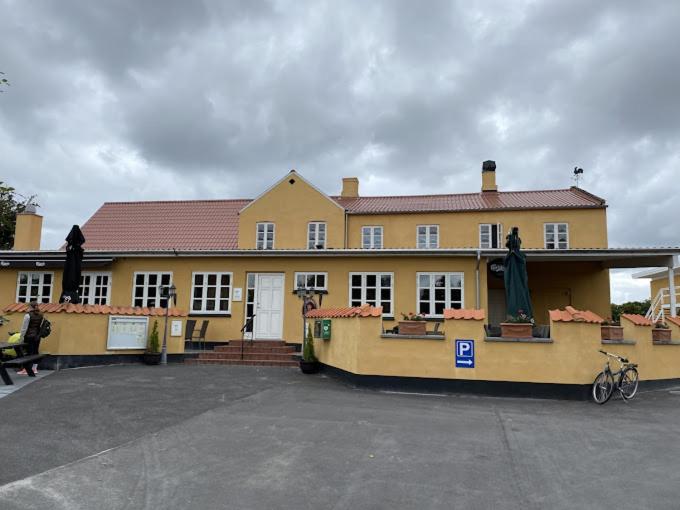 OrøOrø Kro & Hotel的一座黄色的大建筑,前面有一辆自行车停放