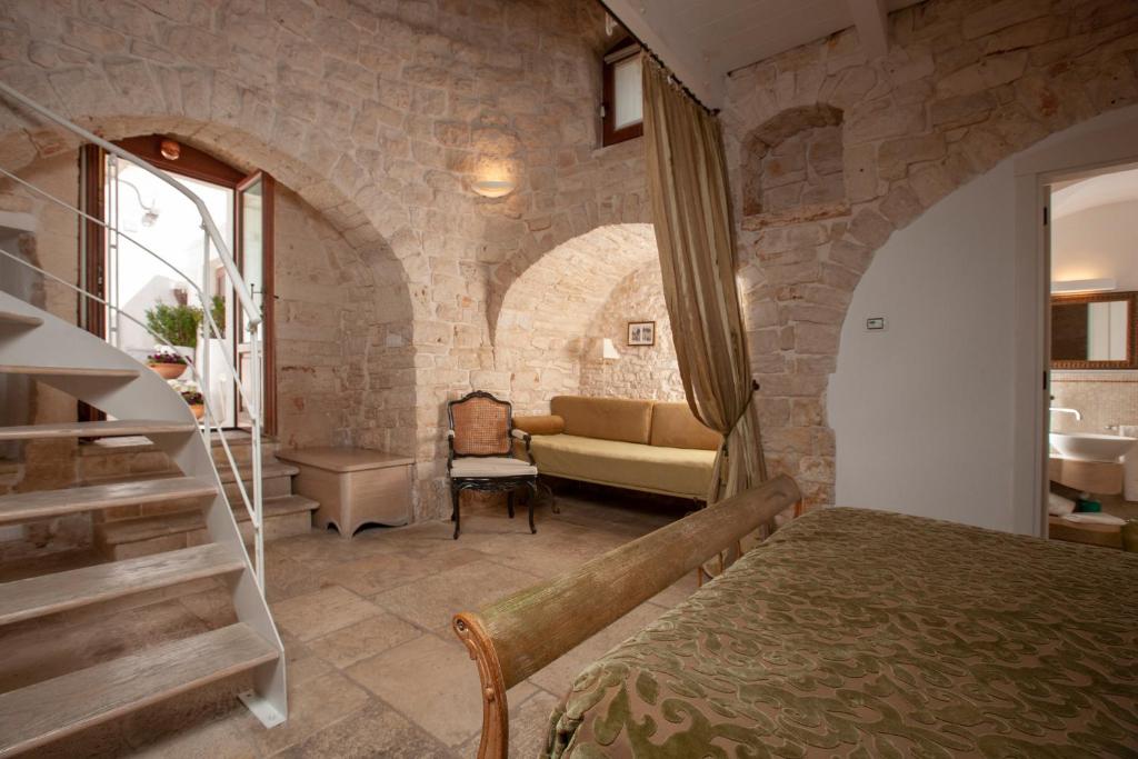 阿尔贝罗贝洛Le Alcove - Luxury Hotel nei Trulli的一间卧室设有石墙、一张床和一张沙发