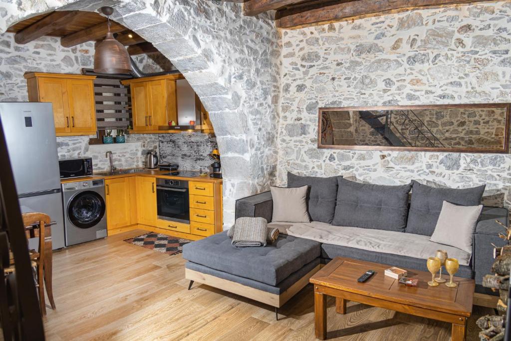 KrásionStefanis Guest House的一间带灰色沙发的客厅和一间厨房