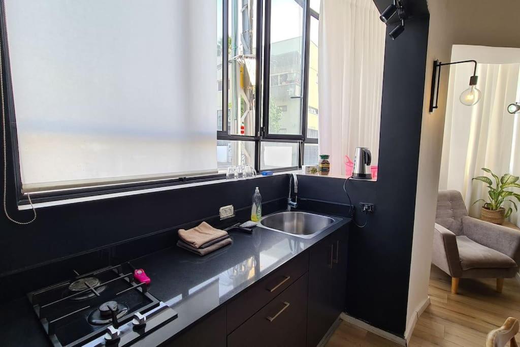 特拉维夫Bright Studio in Shapira的一间黑色的厨房,配有水槽和窗户