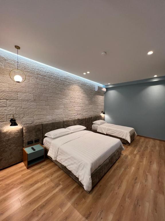 培拉特Bujtina Apsus的一间卧室设有两张床和砖墙