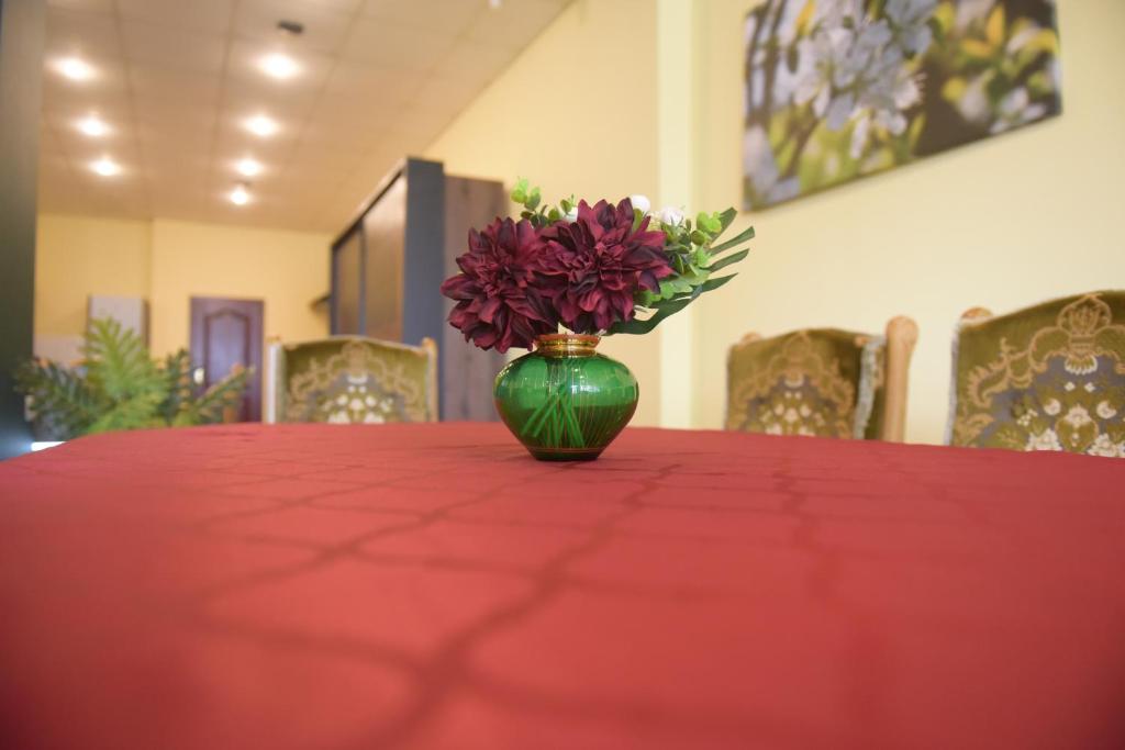 PitschenApartament w Rynku的绿花瓶,花朵坐在红色的桌子上