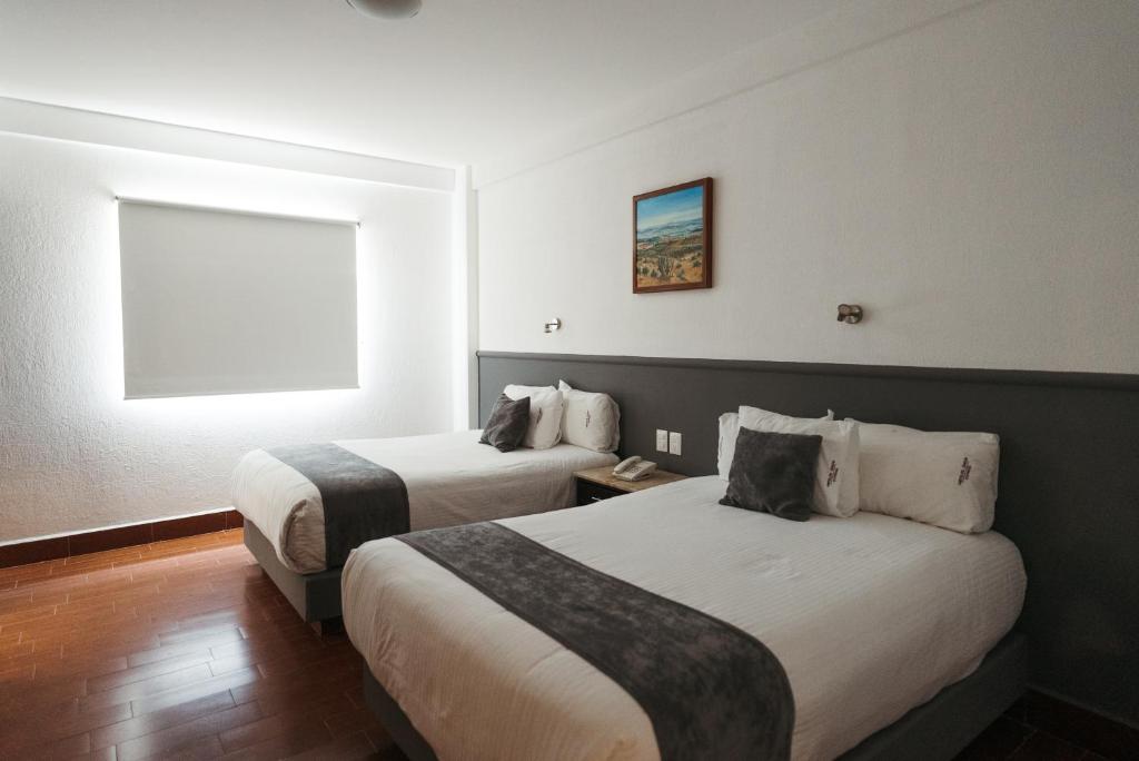 莱昂Hoteles Unico Express的酒店客房设有两张床和窗户。