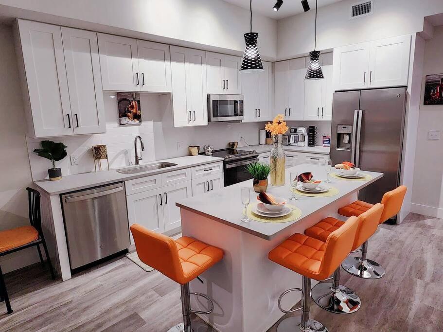 西棕榈滩Luxe & cozy 3Beds,2rooms,EV Gym Near Beaches&Downtown WPB的一间厨房,配有白色橱柜和一个带橙色椅子的岛屿