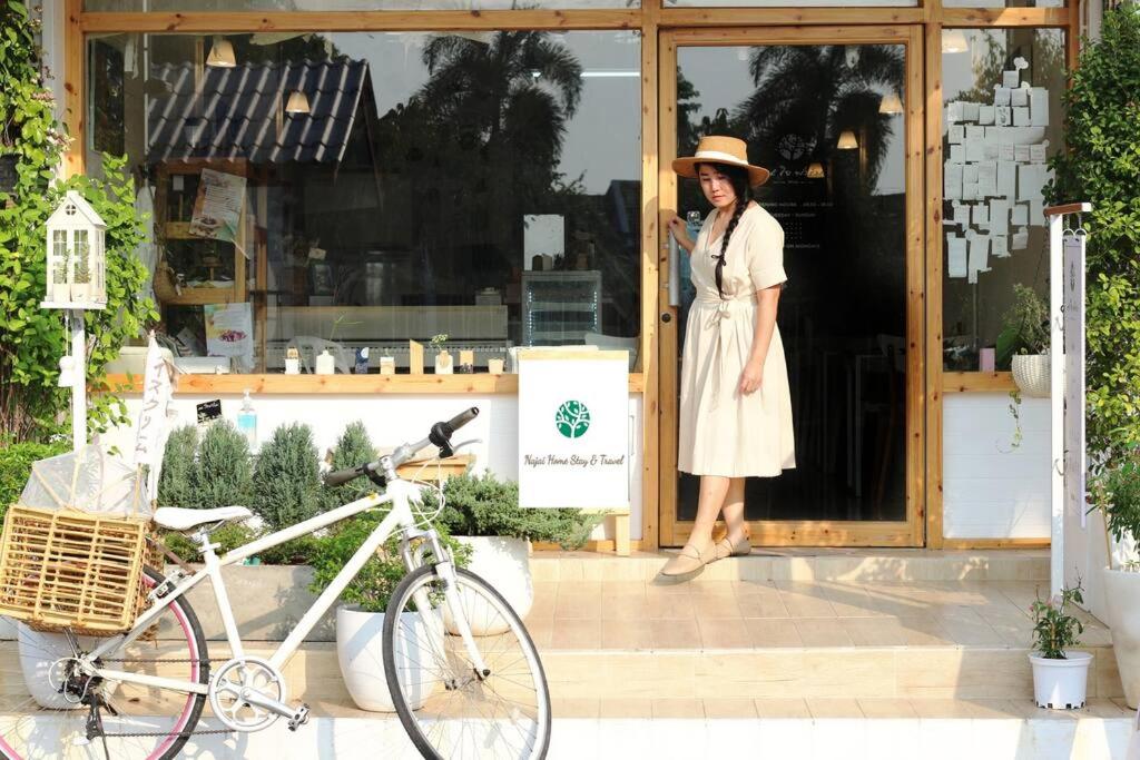南奔Najai Home Stay lamphun的站在商店门口的女人们,骑着自行车