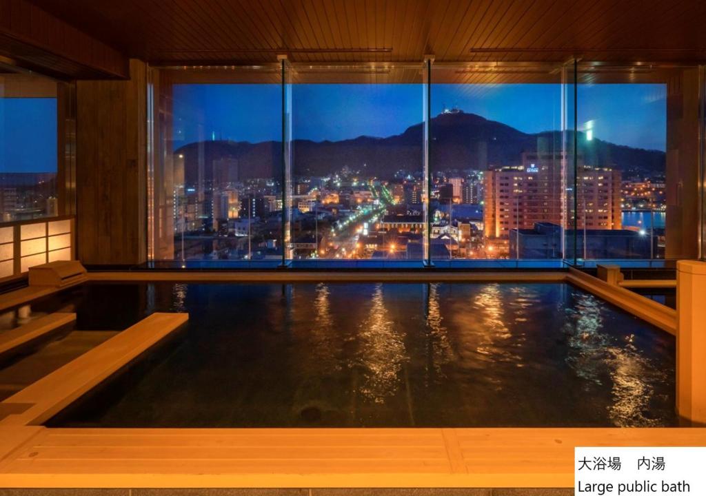 函馆La Vista Hakodate Bay Annex的游泳池,晚上可欣赏到城市景观