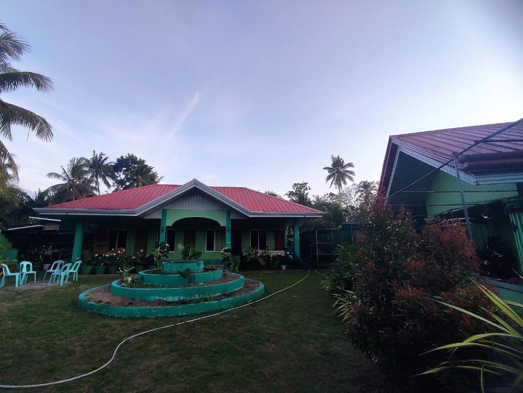 BatuanBARRIL GREEN HOMESTAY的一座红色屋顶的房子和一个院子
