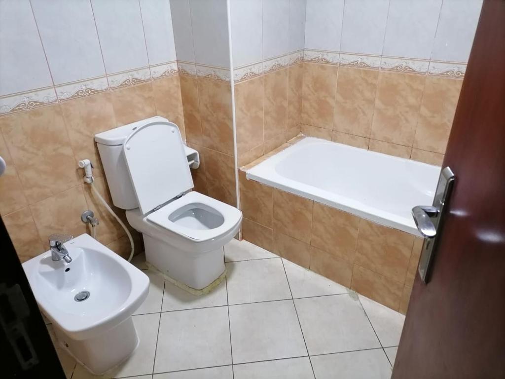 阿布扎比MBZ - Comfortable Room in Unique Flat的浴室配有卫生间、浴缸和水槽。
