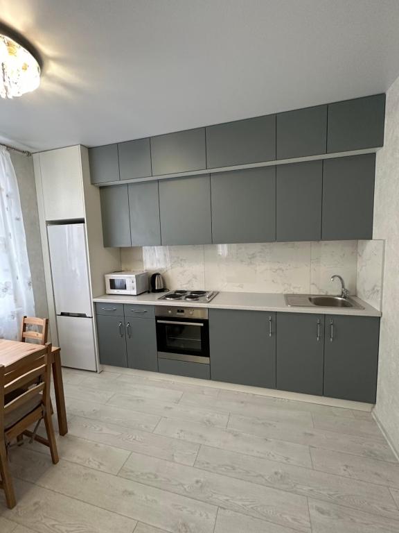 敖德萨Sky apartments Budova的厨房配有灰色橱柜、水槽和桌子