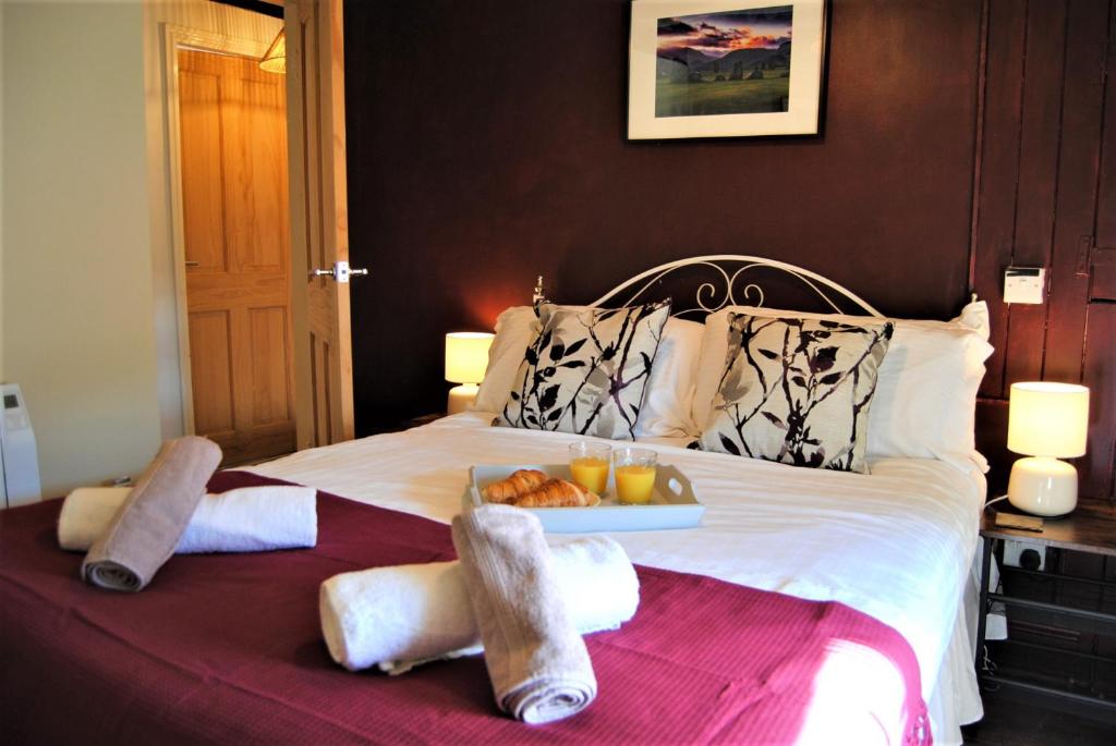 朗日Snowdon Cottage 2的一张带毛巾的床和一盘食物