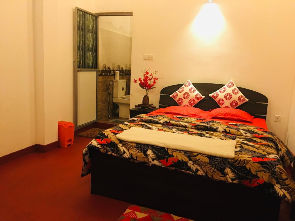 康提Little wood villa Doluwa的一间卧室配有一张带红色枕头的大床