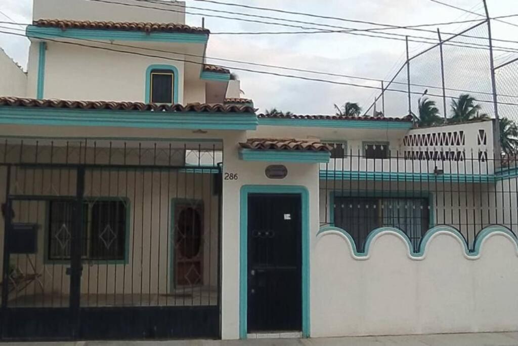 巴拉德纳维达Casa Las Palmas Barra de Navidad, Jalisco.的白色的房子,设有蓝色的门和阳台