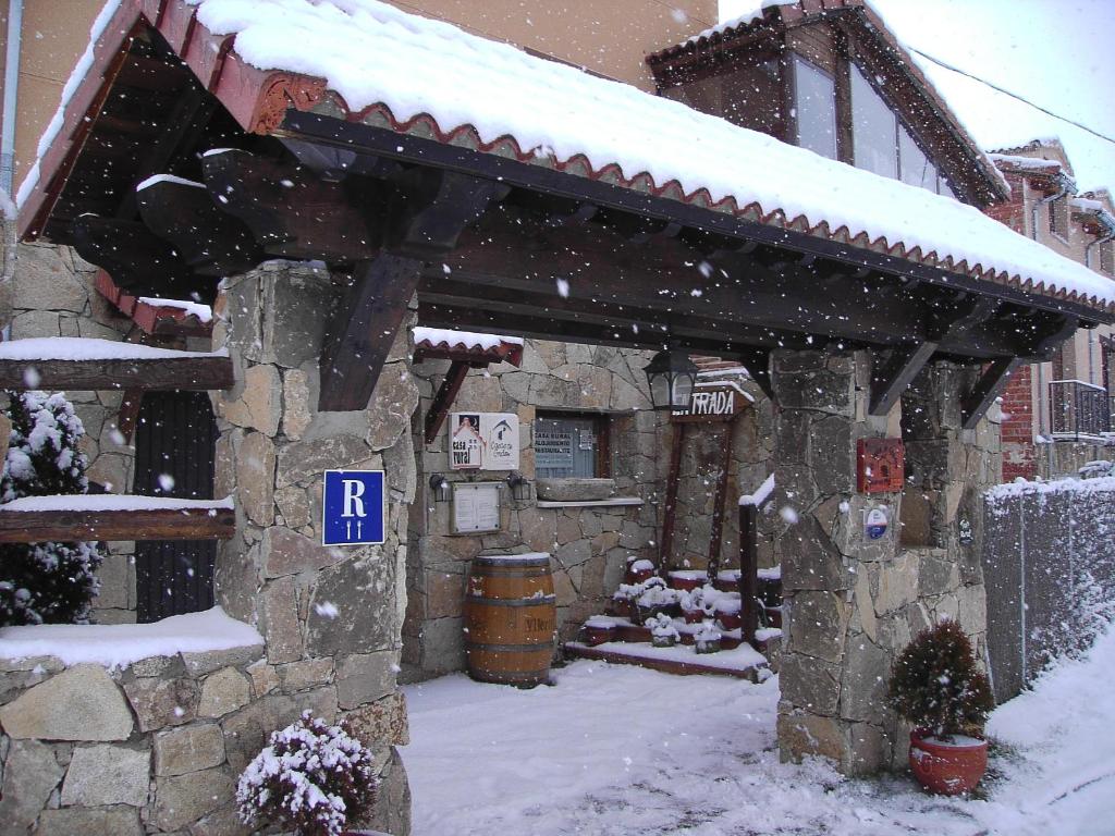 圣马丁-德尔平波Hotel Rural El Yantar de Gredos的一座有雪盖的建筑,前面有一个停车标志