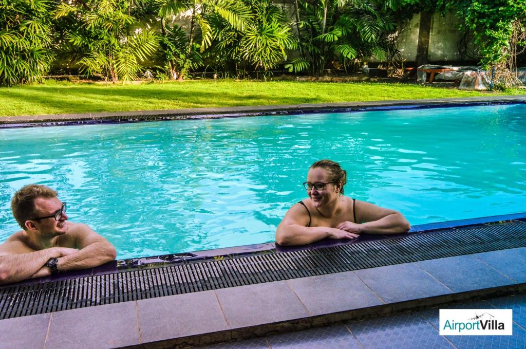 卡图纳耶克机场别墅酒店的两个男人躺在游泳池里