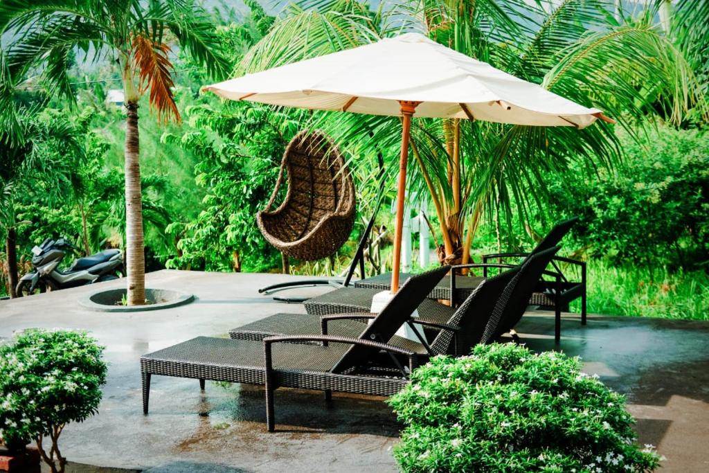 班尤温当Eco Moringa Garden的庭院里摆放着一组椅子和一把遮阳伞