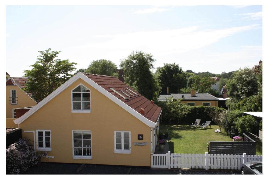 斯卡恩Holiday-Skagen的一座黄色的房子,有白色的栅栏和院子