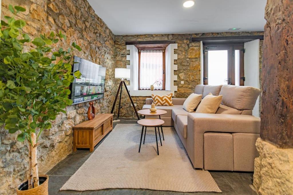 卡马乔Precioso piso estilo rústico a 10 min de Santander的带沙发和砖墙的客厅