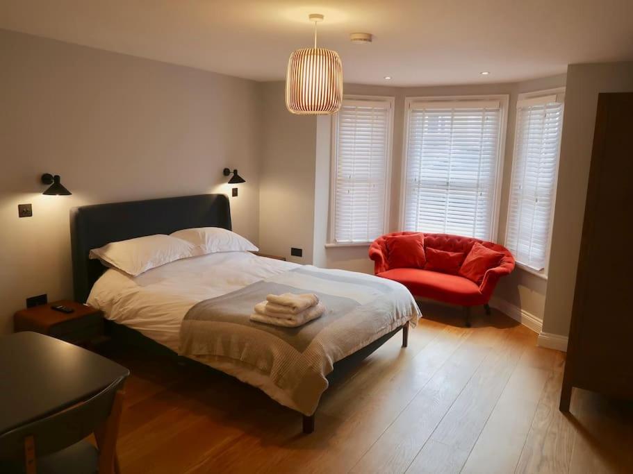 特威克纳姆Stylish Studio Apartment, ensuite, kitchenette的一间卧室配有一张床和一张红色椅子