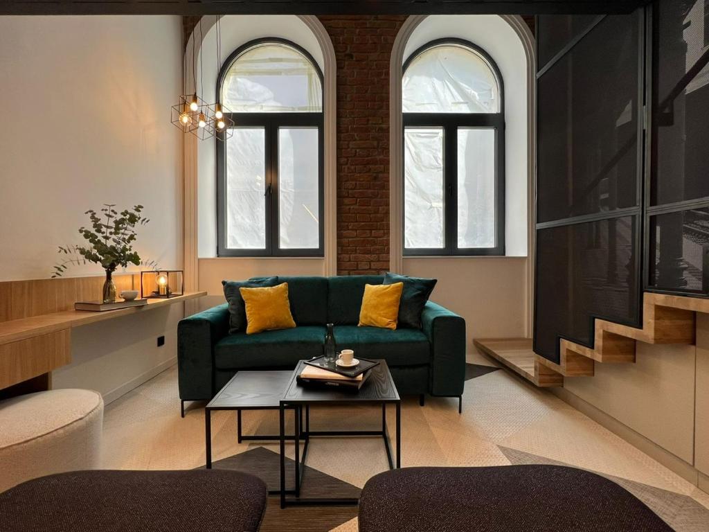 维也纳Fesh Lofts的客厅设有绿色沙发和2扇窗户。