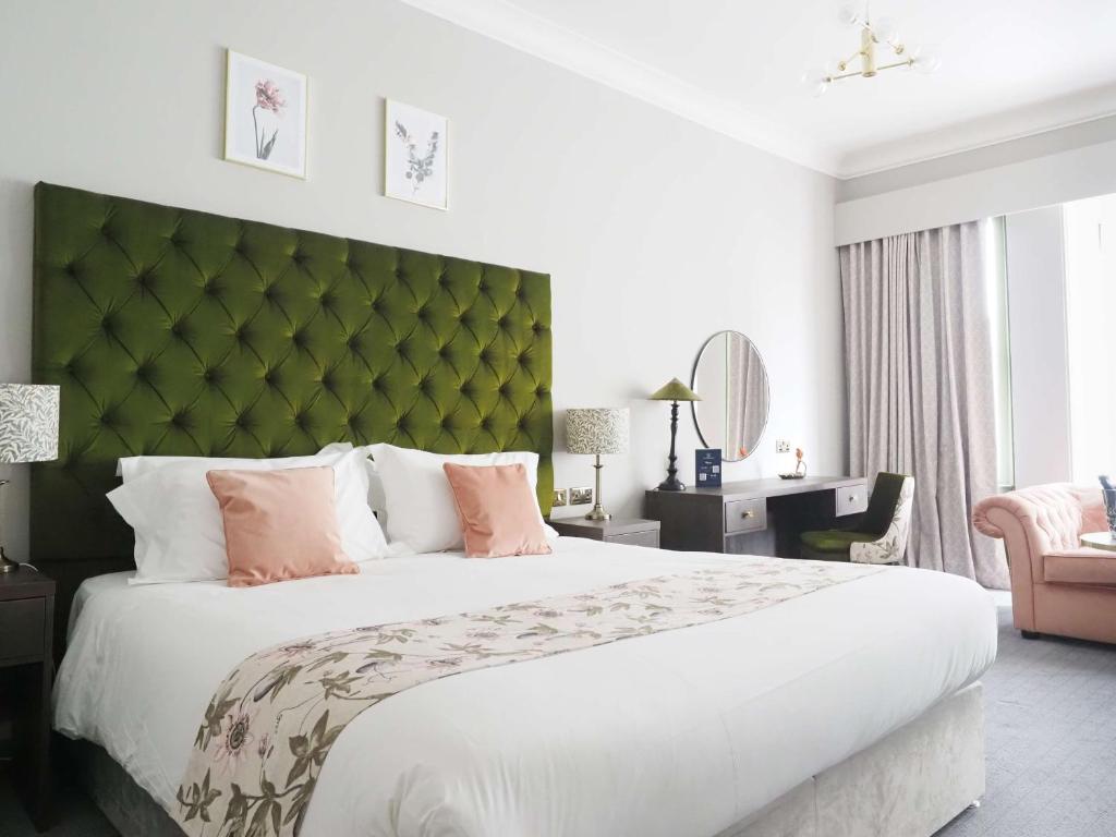 伯恩茅斯Hotel Collingwood BW Signature Collection的一间卧室配有一张大床和绿色床头板