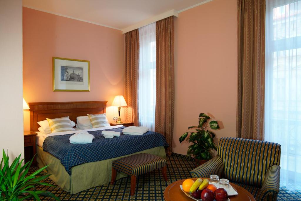 卡罗维发利Hotel Villa Lauretta的酒店客房带一张床、一张桌子和椅子