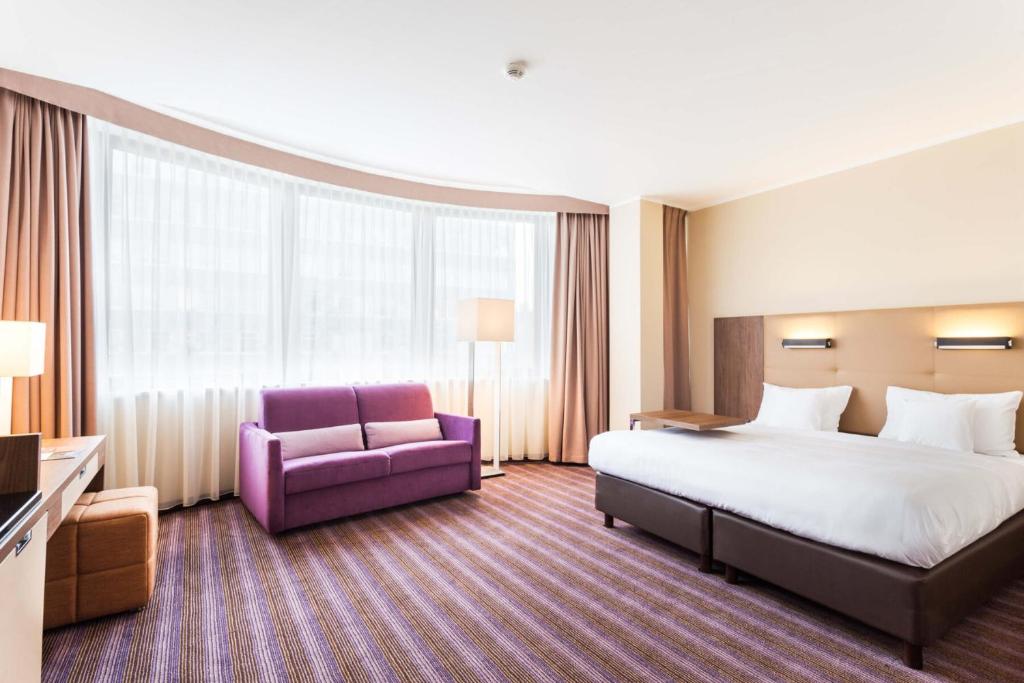 波兹南波兹南德席尔瓦高级酒店的酒店客房,配有一张床和一张紫色椅子