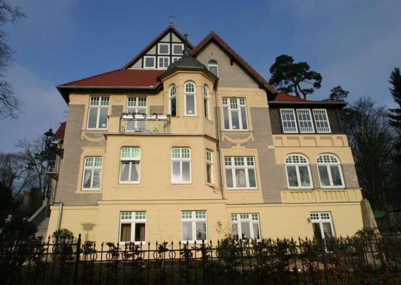 普特布斯Villa Schulenburg in Putbus auf Rügen的大型黄色房屋设有白色窗户和围栏