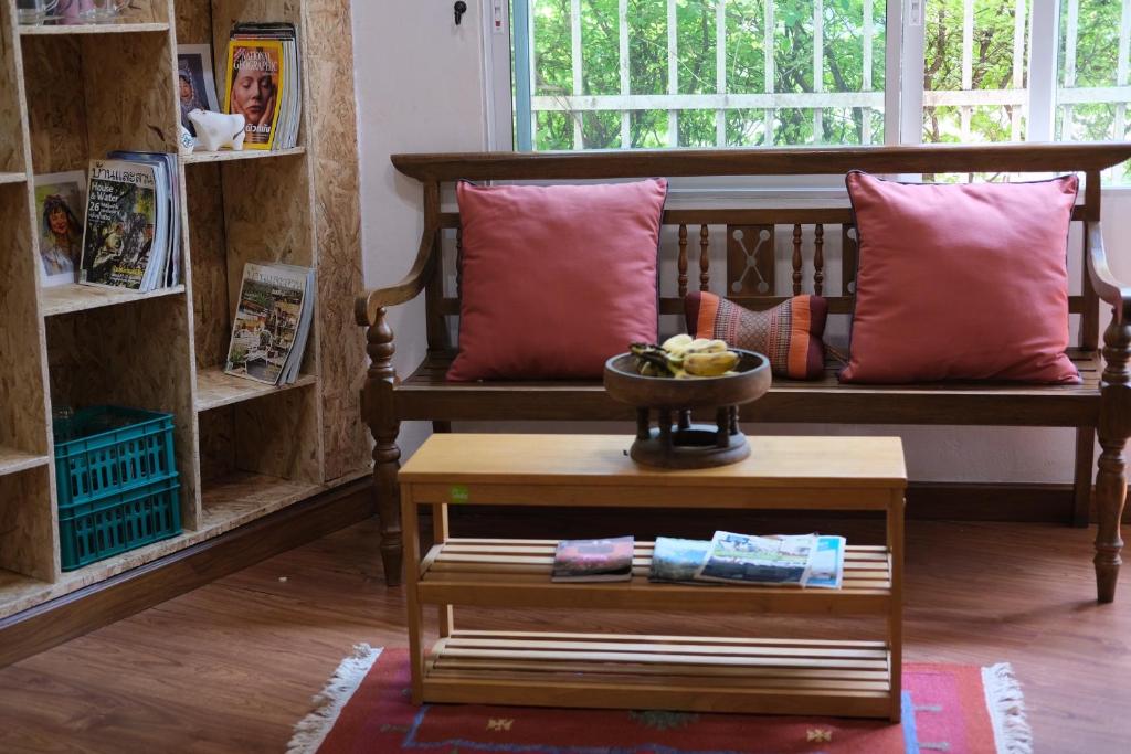 清迈@Home Hostel Wua Lai的客房设有带枕头和桌子的长凳。