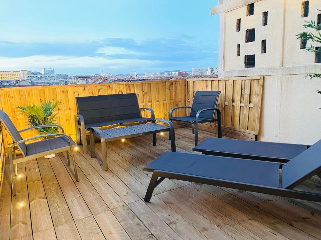 马赛Honoré - Rooftop- Centre Vieux Port的木制甲板上配有桌椅的庭院
