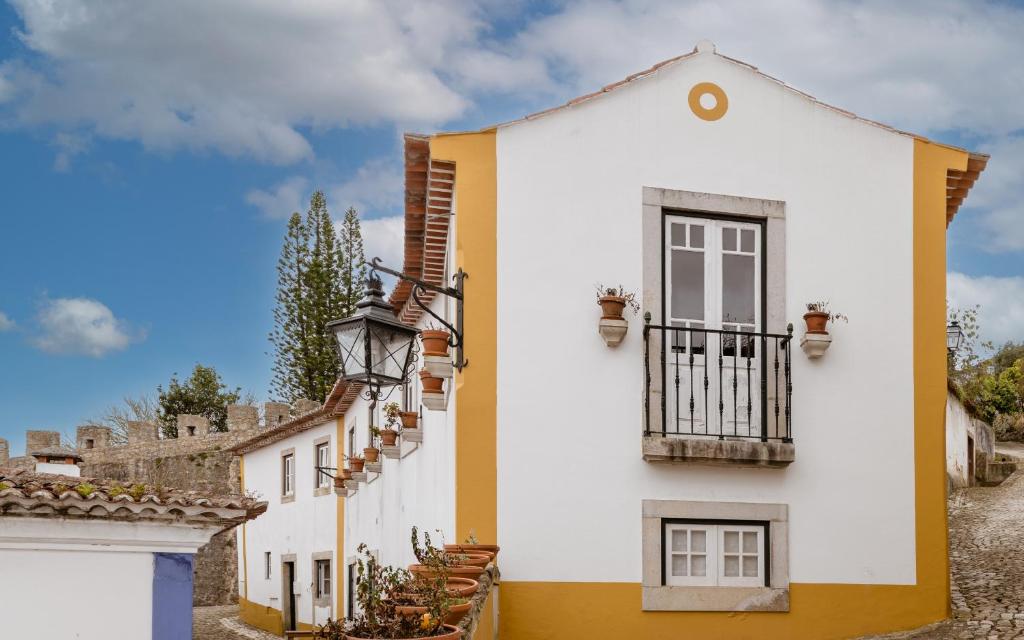 奥比多斯蒂亚戈奥比多斯住宿加早餐旅馆的白色和黄色的房子设有阳台